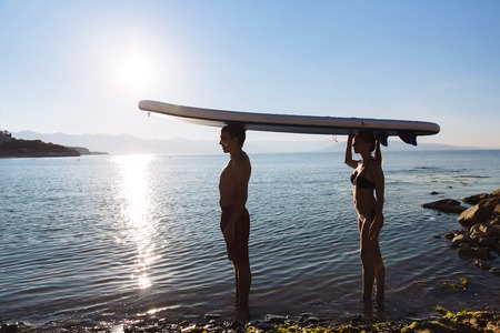 Silhouettes of perfect couple engage standup paddle boardingの写真素材