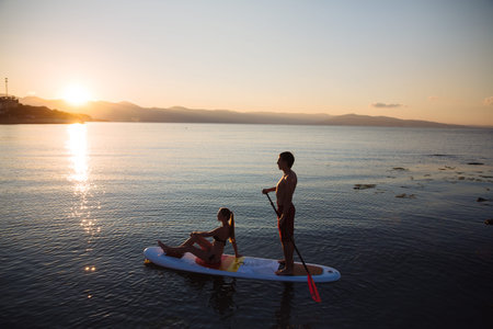 Silhouettes of perfect couple engage standup paddle boarding