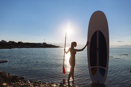 Silhouette of a beautiful woman on stand up paddle board. SUP, concept of lifestyle, sportの写真素材