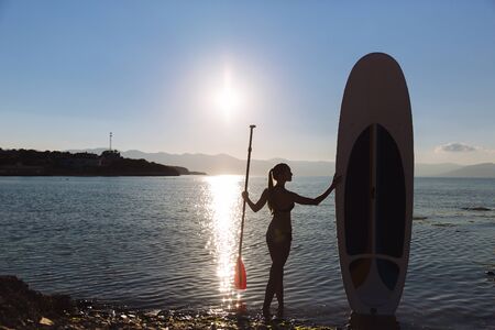 Silhouette of a beautiful woman on stand up paddle board. SUP, concept of lifestyle, sportの写真素材