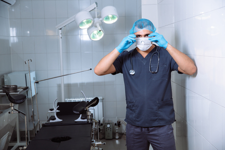 Young man surgeon takes on protective glasses after operation in hospital.の写真素材