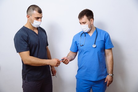 Two surgeons in sterile uniforms with medical instruments on white backgroundの写真素材