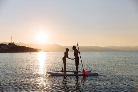 Silhouette of kissing male and female on sup surf at the ocean. Concept lifestyle, sport, love.の写真素材