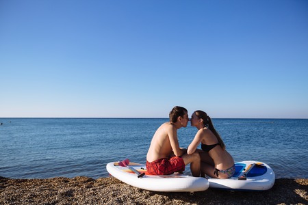 Silhouettes of perfect couple engage standup paddle boardingの写真素材