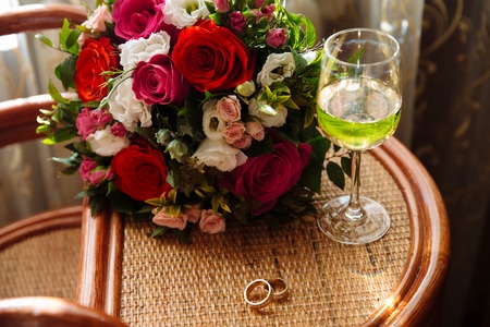 gold wedding ring, a glass of champagne, a bouquet on the tableの写真素材