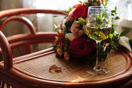gold wedding ring, a glass of champagne, a bouquet on the tableの写真素材
