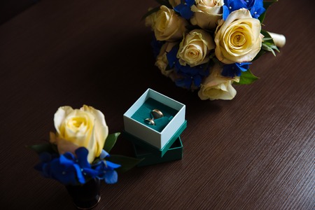 Wedding accessories. Boutonniere, Golden rings, a beautiful bouquet of flowersの写真素材