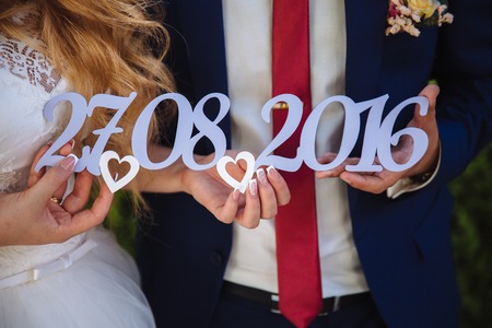 wooden tablet with the date of the wedding in the hands of the bride and groomの写真素材