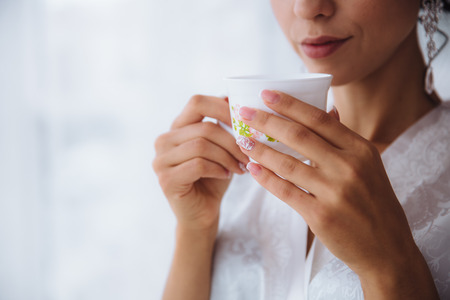 A girl holds a white mug in hands.の写真素材
