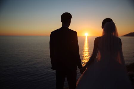 groom and bride are holding hands at sunset, wedding dayの写真素材
