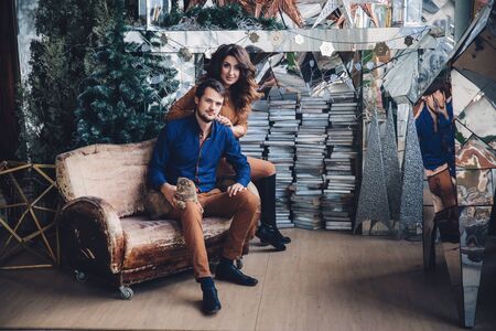 beautiful couple in love with a cat in their arms sitting on the sofa, hugging, smiling and kissing. Family conceptの写真素材
