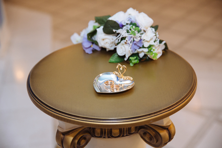 Gold wedding rings on white decorate pillow at wooden backgroundの写真素材