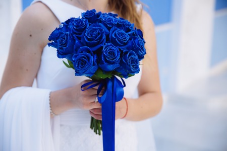Closeup of bride hands holding beautiful wedding bouquet with blue roses. Concept of floristicsの写真素材