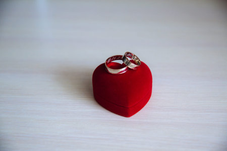 Golden engagement wedding ring in a heart shaped box on white wooden background