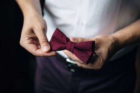Close-up businessman groom holding bow-tie in his hands. Concept of men stylish elegance clothesの写真素材