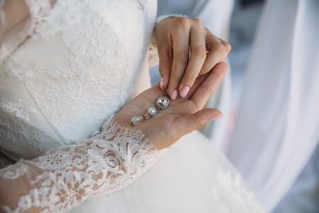 Earrind in the hands of the bride. Concept of jewelry.の写真素材
