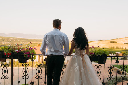 Bride and groom holding hands and turned, back viewの写真素材