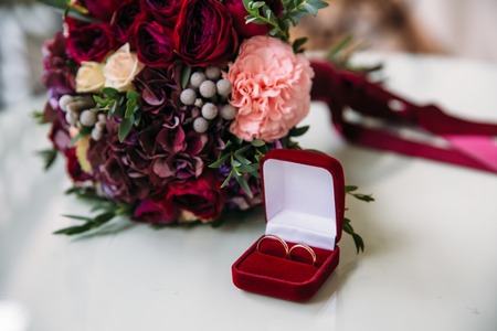wedding golden rings decorated with flowers on white background in red boxの写真素材