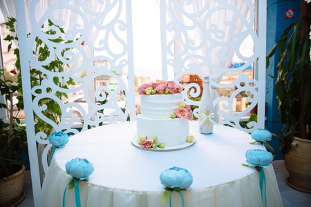 White multilevel wedding cake decorated with pink cream flowers on white table. Candy bar conceptの写真素材