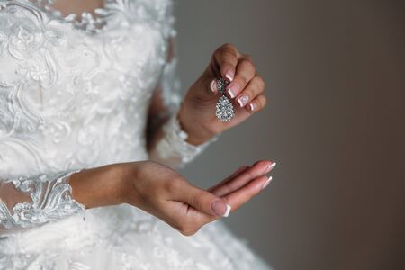 Earrind in the hands of the bride on black background. Concept of jewelryの写真素材
