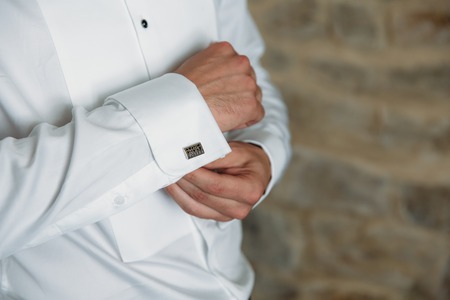 Groom hands with cufflinks. Elegant gentleman clother, white shirt and black beltの写真素材