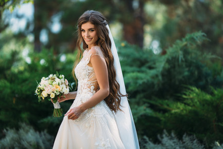 Cute young bride with long hairs holding her wedding bouquet includes white roses and other flowers....