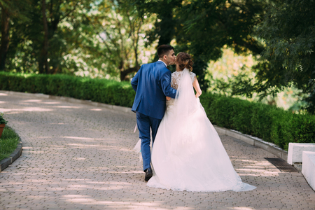 The bride and groom decided to escape from their wedding and are in a hurry so that no one sees them. On the run the man kisses his beloved.の写真素材
