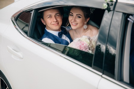 A man and a woman are hugging in the back seat of the car. Portrait of lovers looking at the open window of the car and smiling.の写真素材