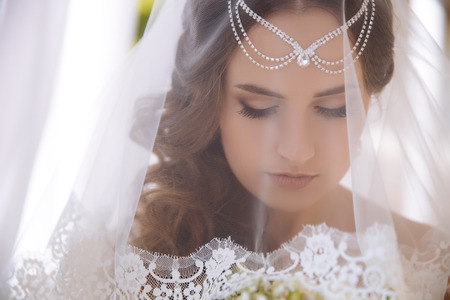 A close-up of the Greek bride covered her face with a white veil and lowered her big eyes down.の写真素材