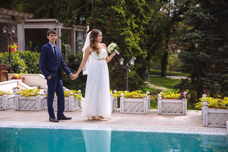 The newlyweds stroll in the mansion, the bride shows her husband a terrace, a swimming pool and a garden.の写真素材