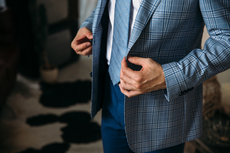 Close-up businessman groom wearing his blue checkered jacket at the morning of wedding day. Concept of men stylish elegance clothes.の写真素材