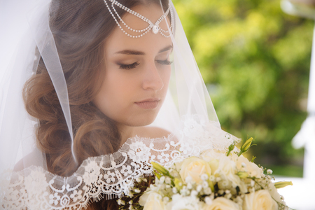 A large captive is the face of a young girl with closed eyes and long black eyelashes. The bride lowered her veil, covered her eyes with excitement on the wedding day. The hair was decorated with beads.の写真素材