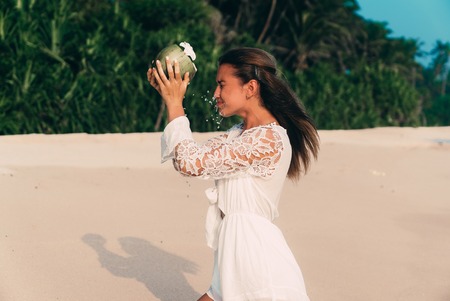 A young girl wanted to drink beautifully water from the coconut, but ridiculously poured a face.の写真素材