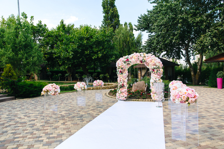 The snow-white path that leads to the altar. Wedding decorations, a wedding arch decorated with peonies, bouquets of flowers. The concept of wedding style, florist.の写真素材