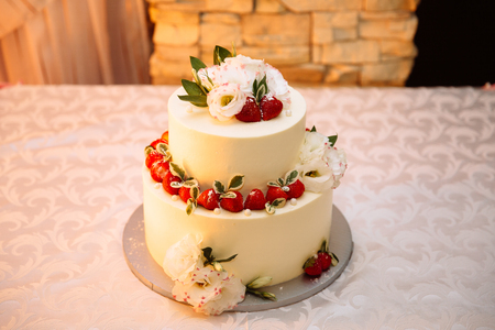 Close-up top view of a wedding three-story cream cake. Confectionery asteroids and dessert decorations for newlyweds, decorated with strawberries and white delicate flowers.の写真素材