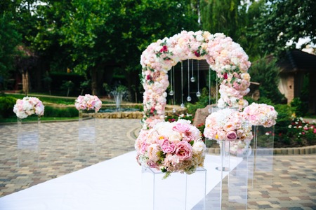 The concept of wedding decor, street decoration, wedding arch is decorated with flowers - pink and white peonies. Wedding day, ceremony place for the bride and groom, decor, flowers, florists.の写真素材