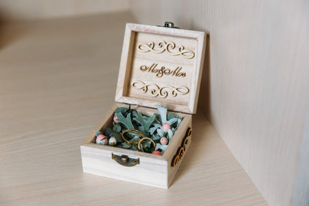 A close-up of the gold rings lie in a jewelry box adorned with hvoy branches, engraved with Mr. and...