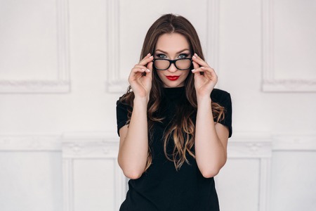 A beautiful girl with clean and healthy skin, bright lip makeup, wears glasses. Young stylish teacher portrait.の写真素材