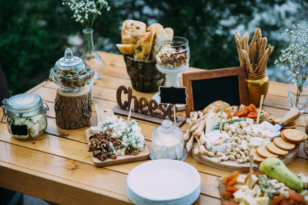 Cheese bar of several kinds of cheese, snacks, honey, nuts decorated on wooden table at the wedding...