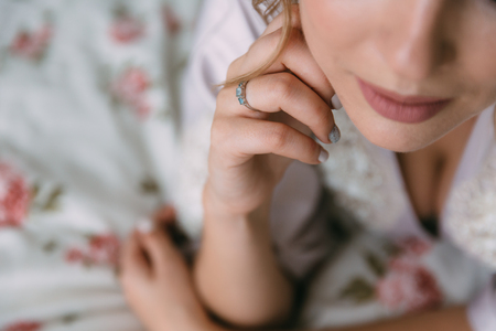 Close-up earrind in the hands of the bride on her ear. Concept of jewelry. Morning preparation of the bride for marriage.の写真素材