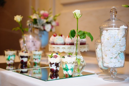 Candy bar, a table with sweets and desserts on the table. Buffet with delicious cupcakes, cake pops, biscuits, flowers.の写真素材