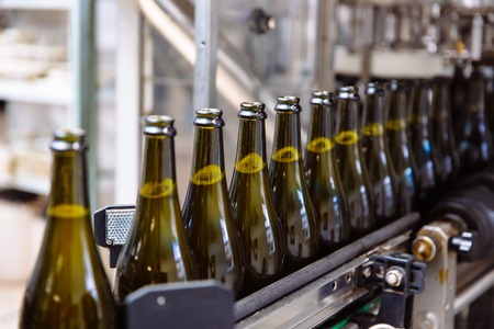 Glass bottles on the automatic conveyor line at the champagne or wine factory. Plant for bottling alcoholic beverages.