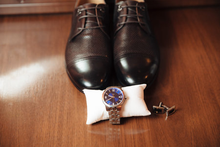 Mens leather shoes, watches and cufflinks on the background of a brown table. Clothing accessories...