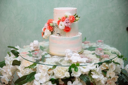 Multilevel wedding cake decorated with flowers stands on a table. Concept of eating, sweets and desserts at a party.の写真素材