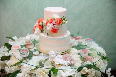 Multilevel wedding cake decorated with flowers stands on a table. Concept of eating, sweets and desserts at a party.の写真素材