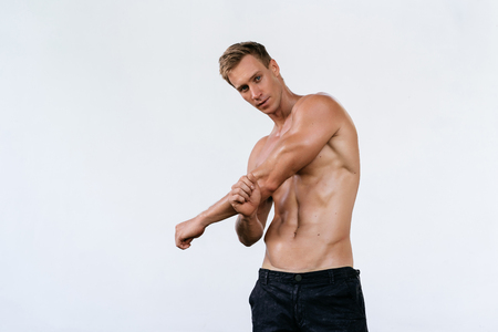 Sexy athletic man with naked torso on white background. Fashion portrait of sporty healthy guyの写真素材
