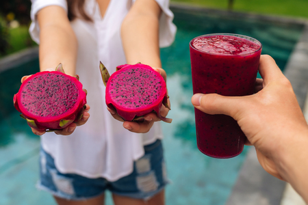 Close up glass of dragon fruit smoothie and fruit in woman and man handsの写真素材