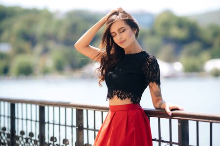 Beautiful happy girl posing outdoor wearing red skirt and black blouseの写真素材