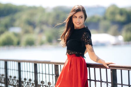 Beautiful happy girl posing outdoor wearing red skirt and black blouseの写真素材