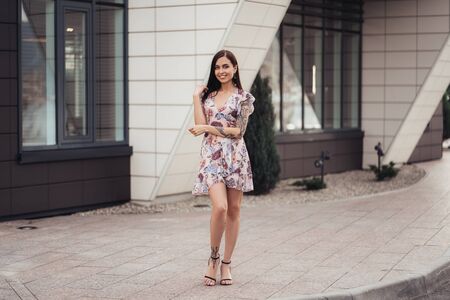 Attractive brunette girl in colored dress posing near business center.の写真素材